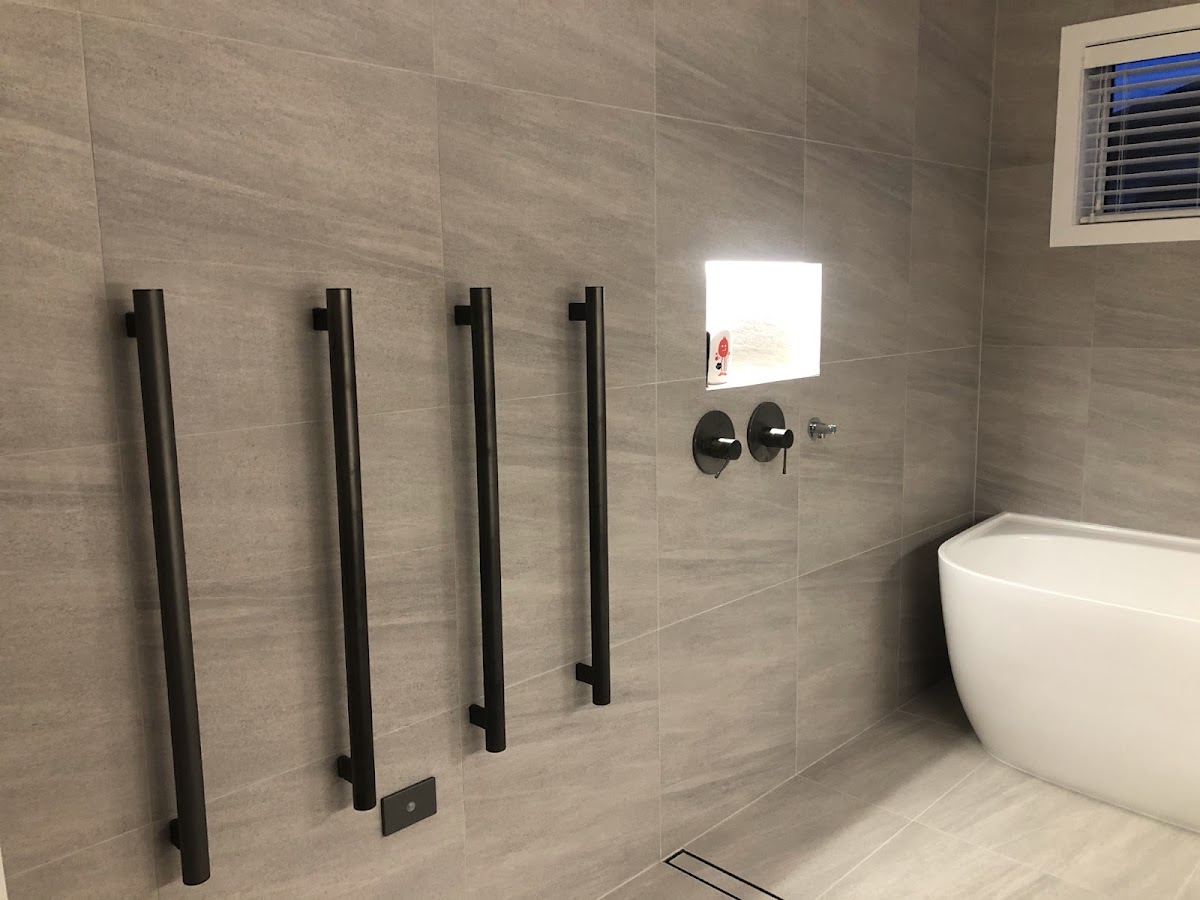 Heated towel rails and illuminated wall niche in a tiled bathroom